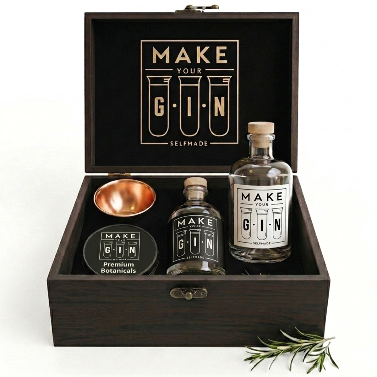 Studioaufnahme der geöffneten, dunkelbraunen Make Your Gin Holzbox auf weißem Grund, bestückt mit einer Glasflasche, einer Gewürzdose und einem kupferfarbenen Messbecher.